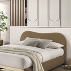 Close-up of queen bed frame with curved velvet headboard and layered bedding. Upholstered wood frame adds elegance to bedroom interiors.