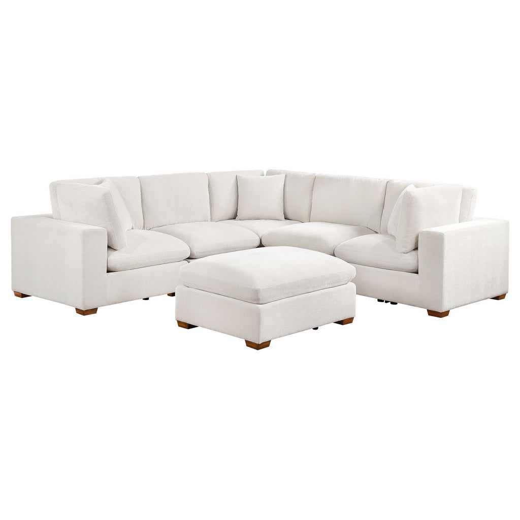 Ivory 6-piece modular sectional sofa upholstered in fabric with tapered wooden legs and a matching ottoman.