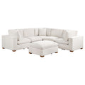 Ivory 6-piece modular sectional sofa upholstered in fabric with tapered wooden legs and a matching ottoman.