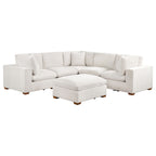 Ivory 6-piece modular sectional sofa upholstered in fabric with tapered wooden legs and a matching ottoman.