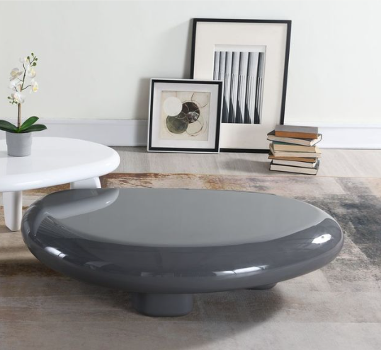 Charlene Gloss Coffee Table in gray with high gloss finish and rounded shape, styled in a modern living room with decor and books.
