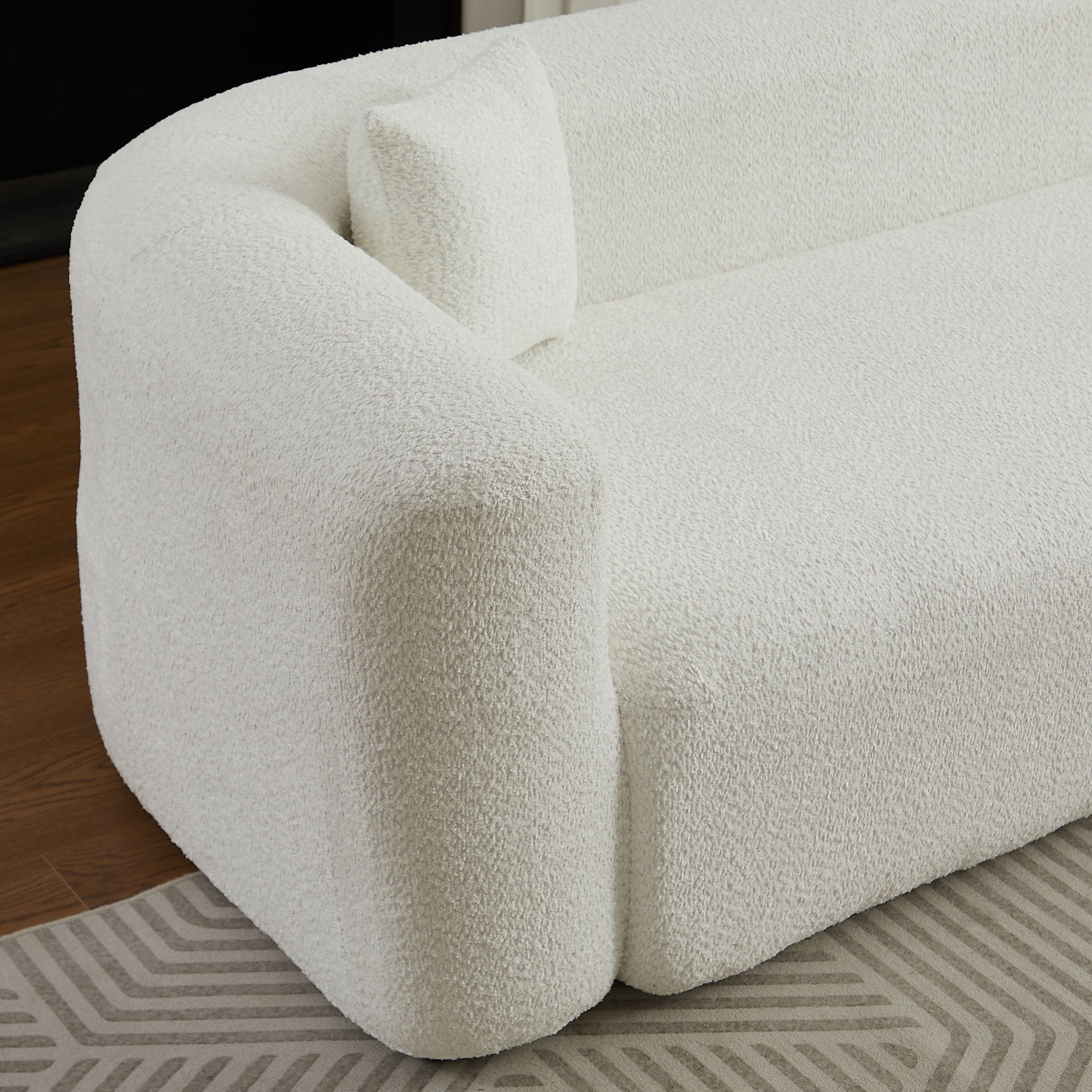 Close-up of the left armrest and cushion on the beige chenille modular sectional sofa, highlighting its rounded modern shape.