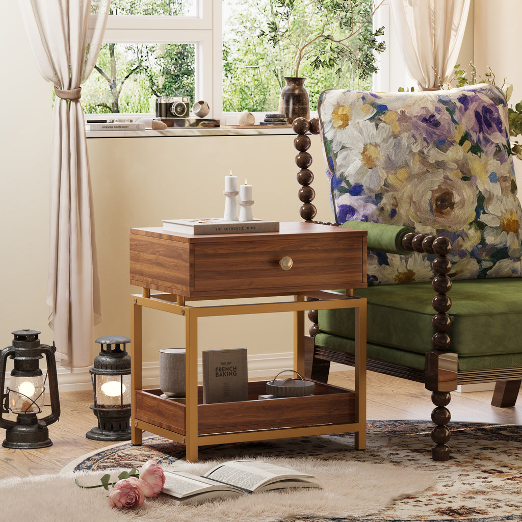 Modern walnut end table with a drawer and open shelf, featuring a sleek gold metal frame beside a floral armchair.