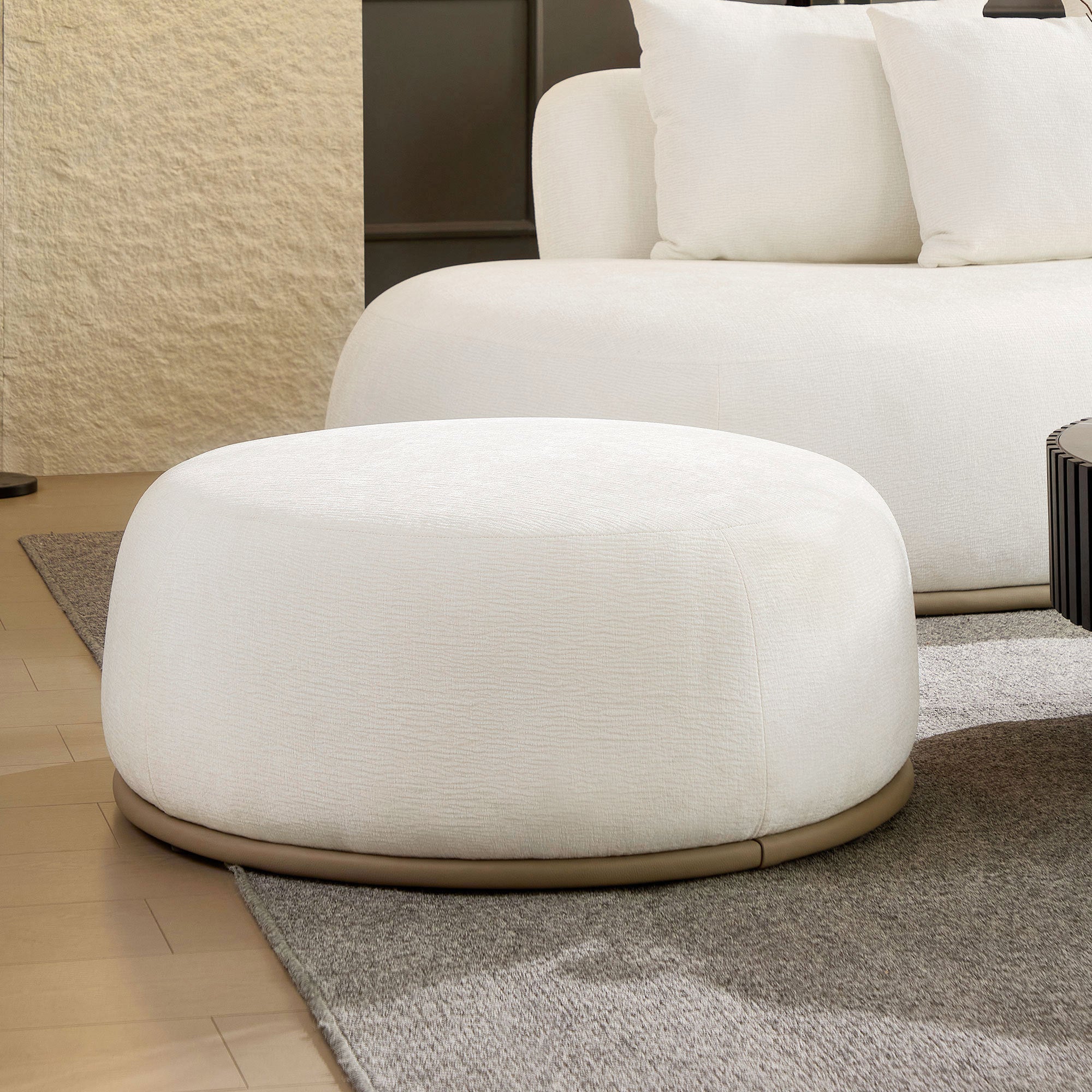 Close-up of the beige ottoman from the oversized L-shape sectional sofa set, showcasing its rounded shape and textured upholstery.