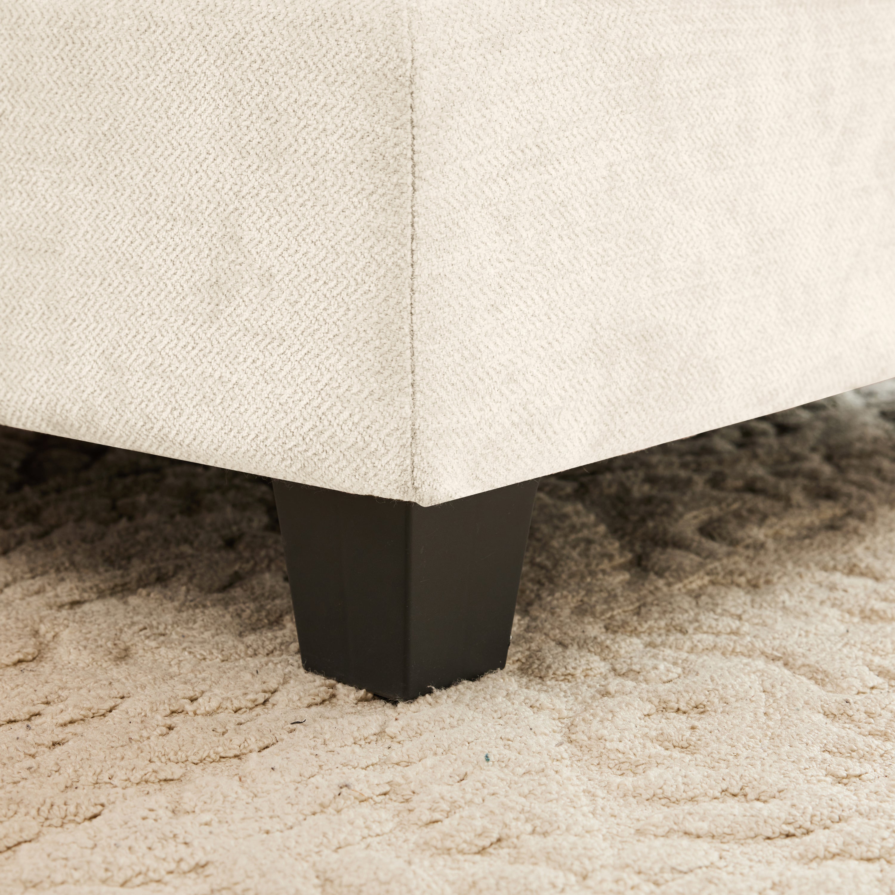 Detail of the sturdy black legs and chenille upholstery on the Modular L-Shaped Sofa - Sectional Couch, placed on a textured rug.