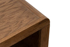 Close-up of Haven Oak Coffee Table corner, displaying smooth curved edge and rich bourbon finish on oak wood grain.