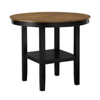 Round counter height dining table with black legs and wood grain top, featuring a central storage shelf for added functionality.