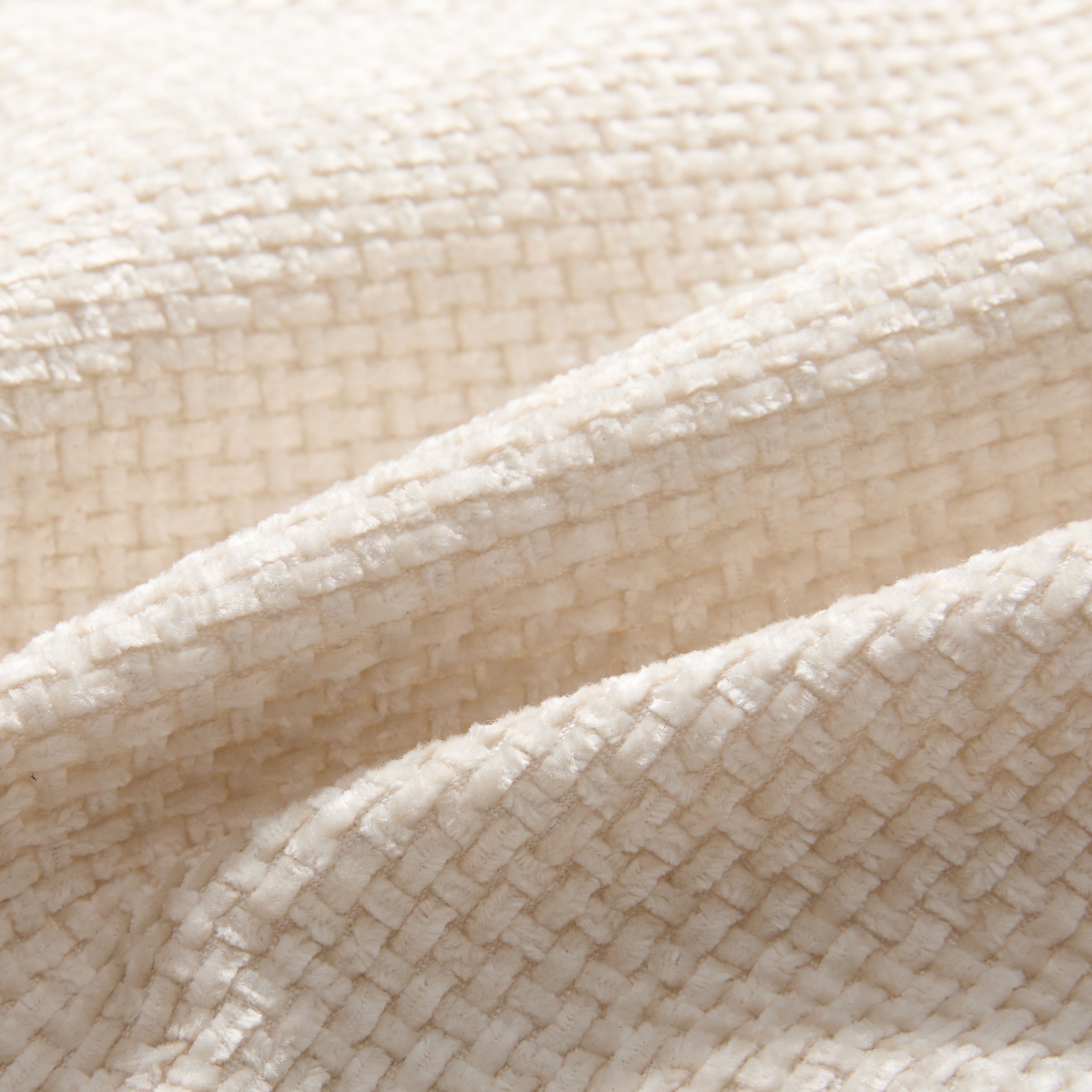 Close-up of textured cream fabric on modular sectional sofa. Durable upholstery ideal for stylish and comfortable living room use.