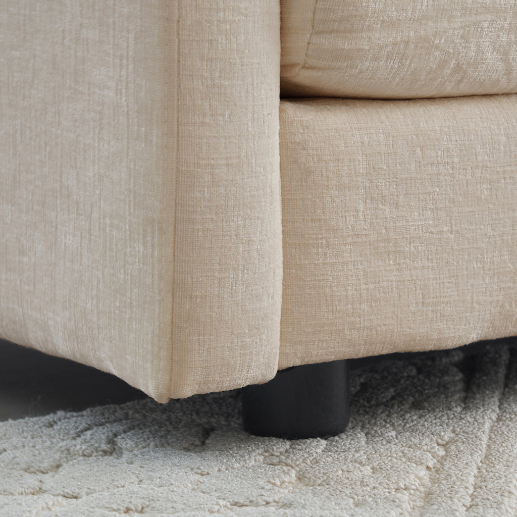 Close-up of black sofa leg and textured beige chenille upholstery. Durable base supports the modern sectional sofa design.