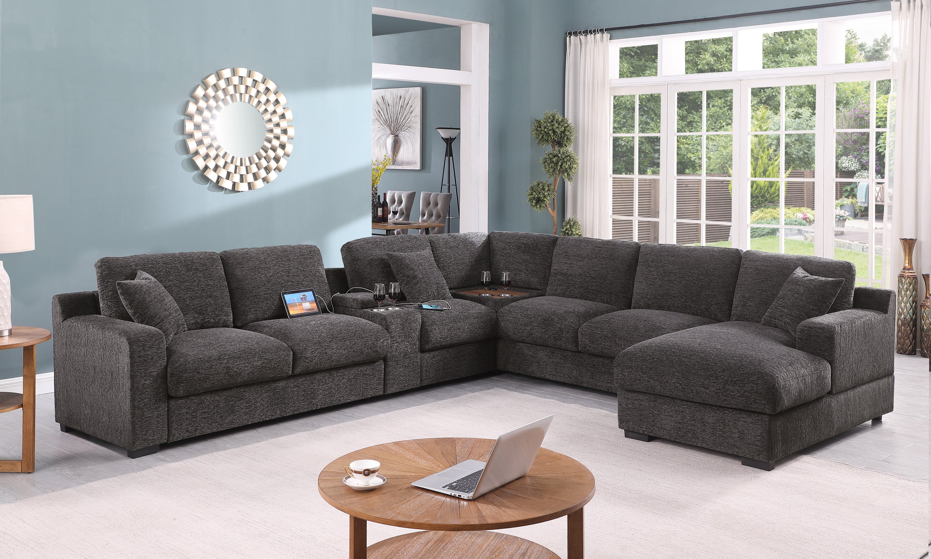 Gray chenille sectional sofa with right-facing chaise, cupholders, and charging ports in a modern living room with large windows.