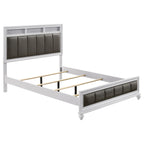 White Eastern king bed frame with tufted dark leatherette panels, metallic accents, and wood construction.