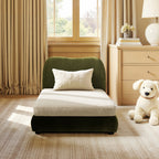 Modern olive green performance velvet pet sofa with a plush cream cushion and matching lumbar pillow in a cozy room.