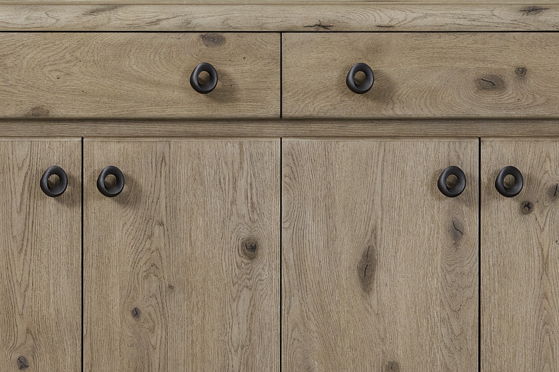 Close-up of Knotty Oak Veneer Server - English Style featuring natural wood grain texture and round black metal handles on drawers and cabinets.