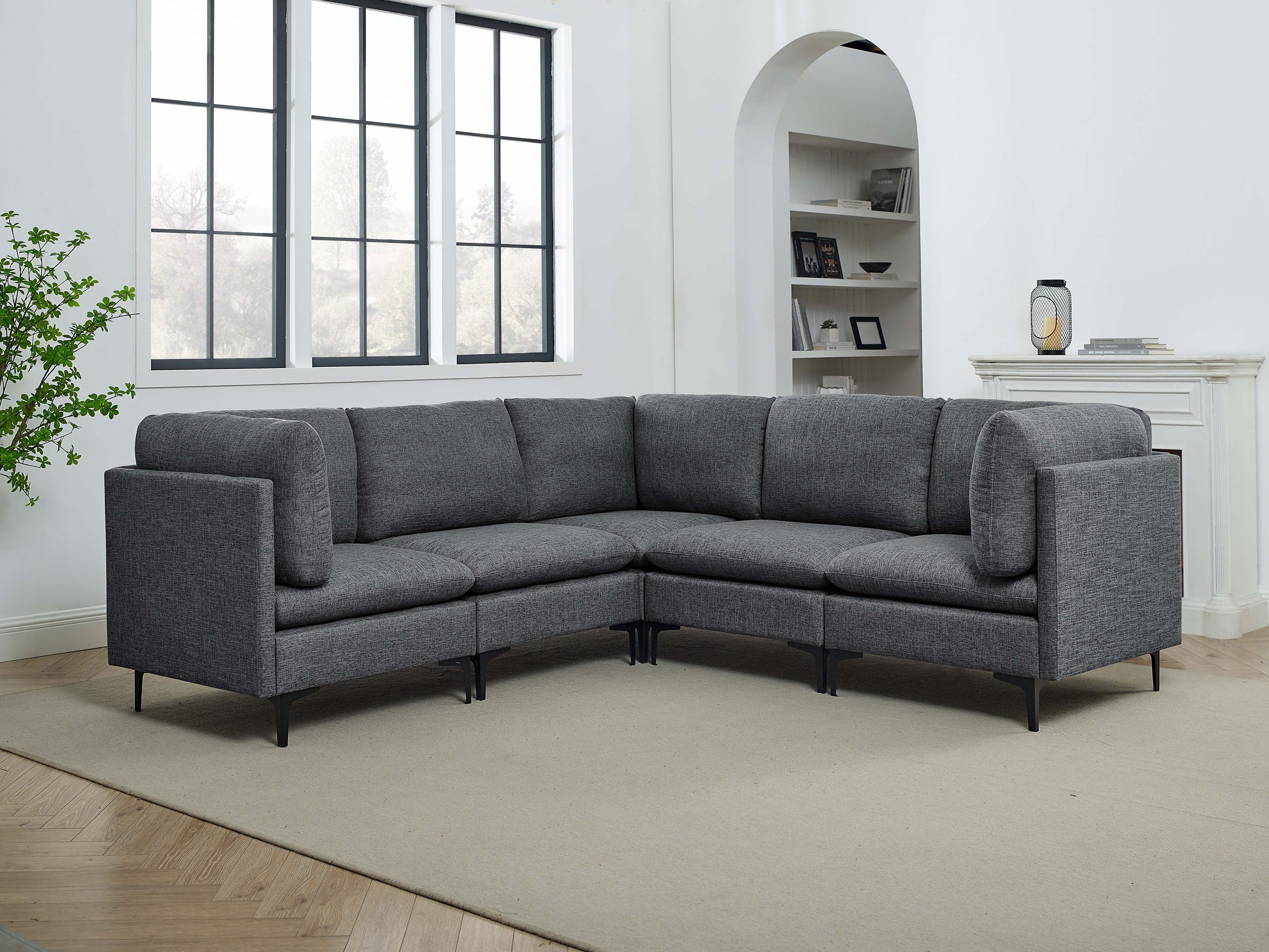 Modern dark gray linen sectional sofa with plush cushions and slim black metal legs in a bright living room.