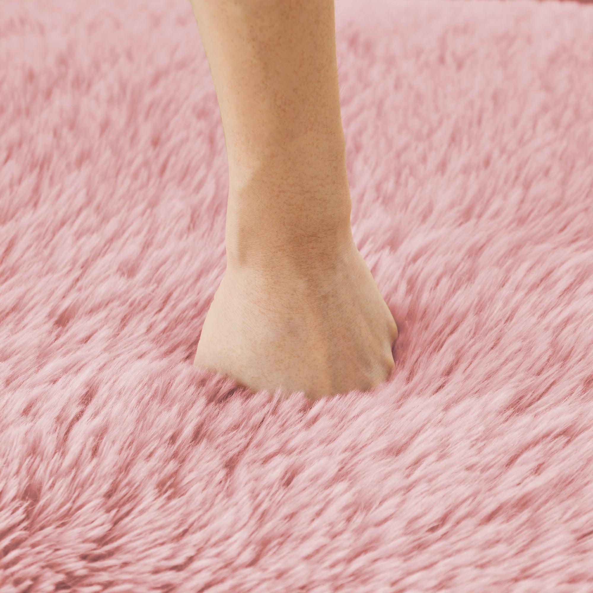 Hand pressing into pink plush sofa cushion, demonstrating the softness and high-density foam of the non-slip, no-assembly sofa.