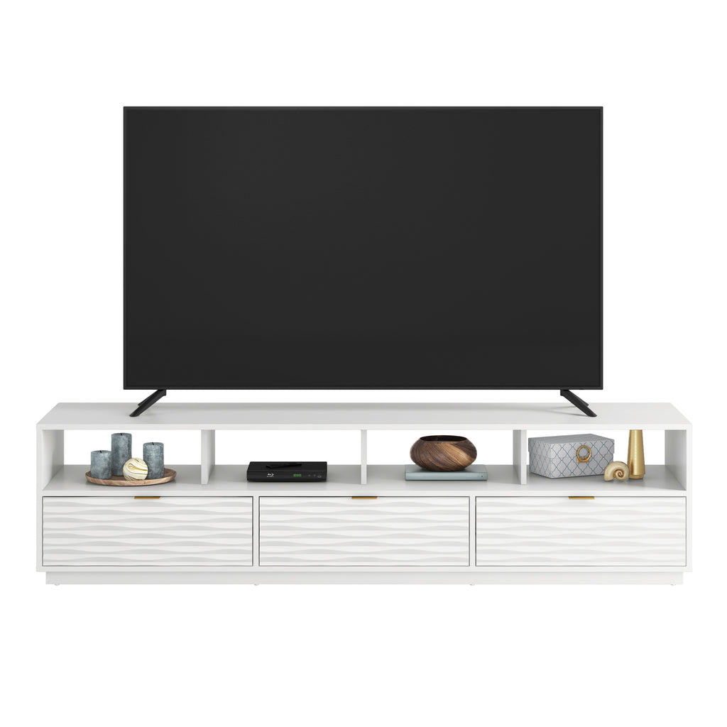Front view of White Coastal Credenza supporting a large TV, featuring ample open shelving and three wave-textured drawers.
