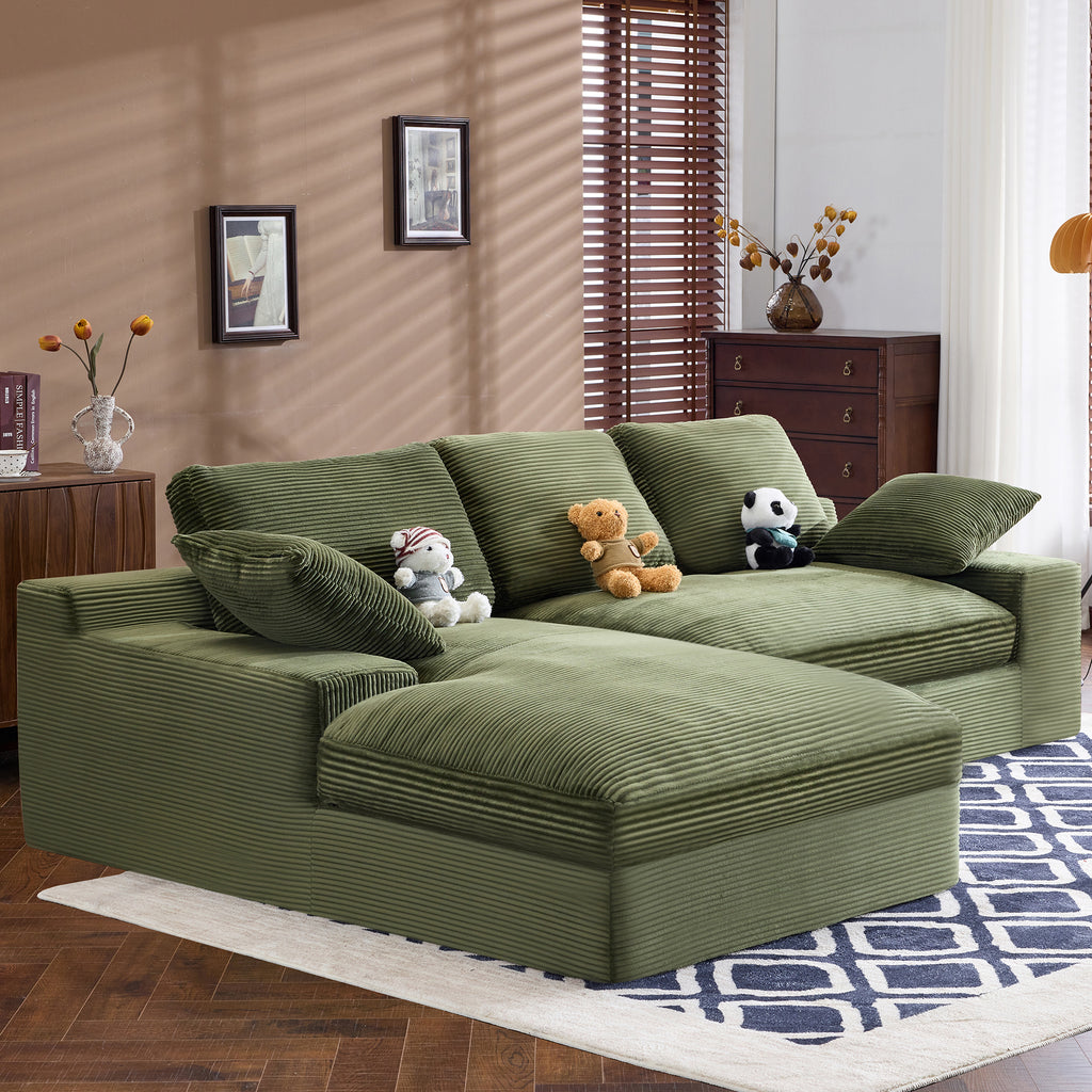 Green corduroy sofa with stuffed toys and soft pillows, placed on a patterned rug. Comfortable and durable for everyday use.