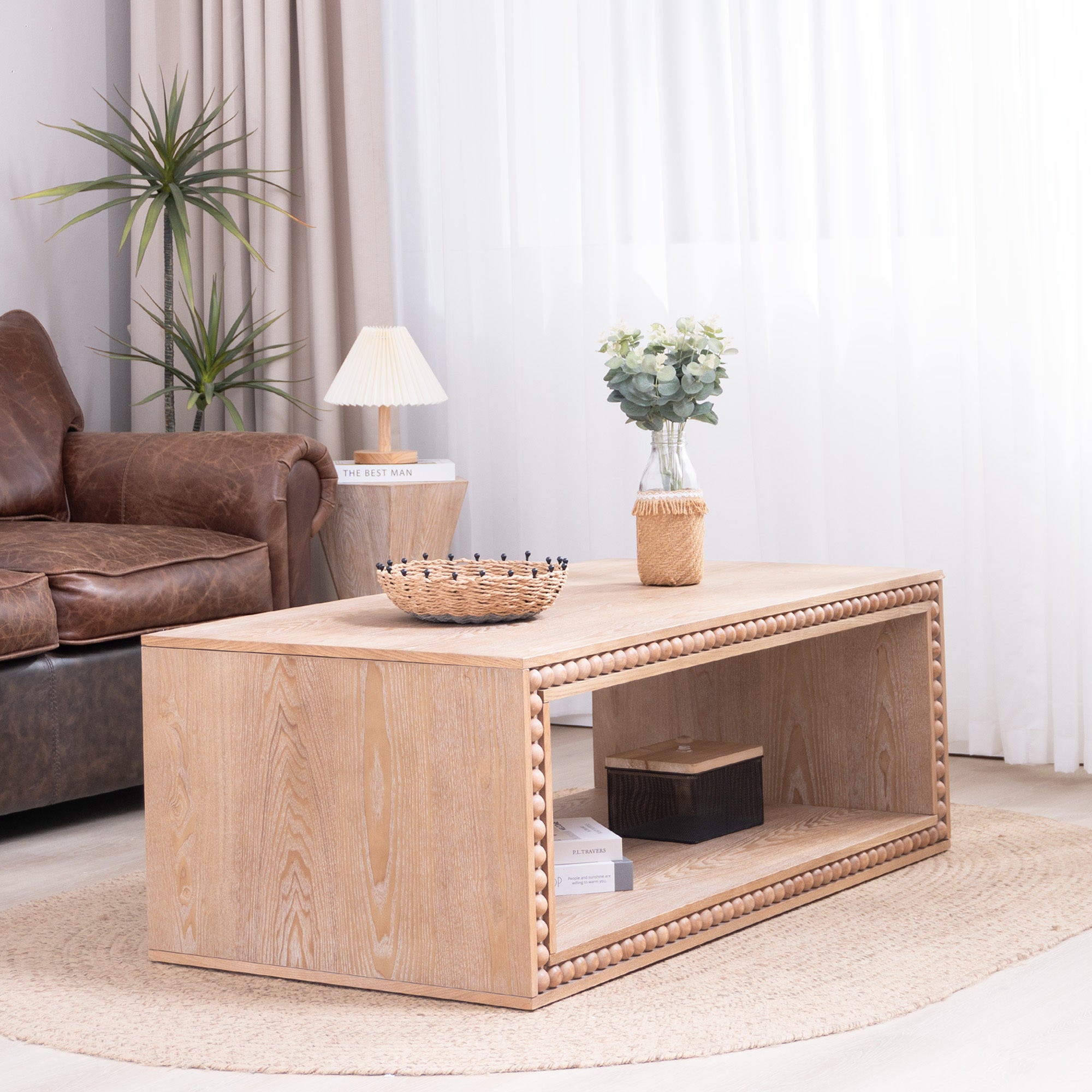 Modern farmhouse coffee table with natural wood finish, styled with decor on top and books on the open shelf in a bright room.