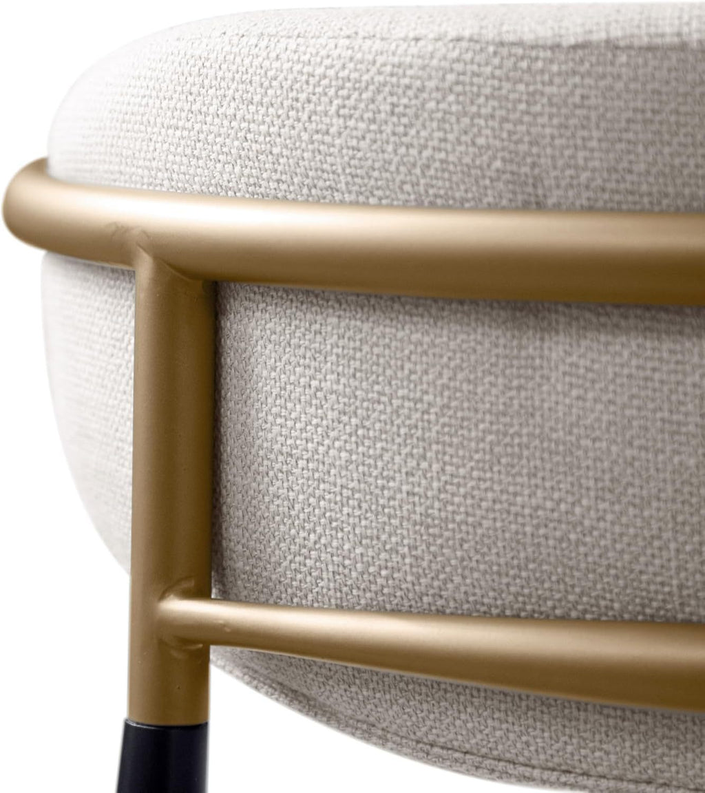Close-up of the gold metal frame and textured beige upholstery on the backrest of a contemporary counter height chair.
