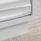 Close-up of the textured drawer front on the white coffee table, showcasing the coastal wave design and smooth white finish.
