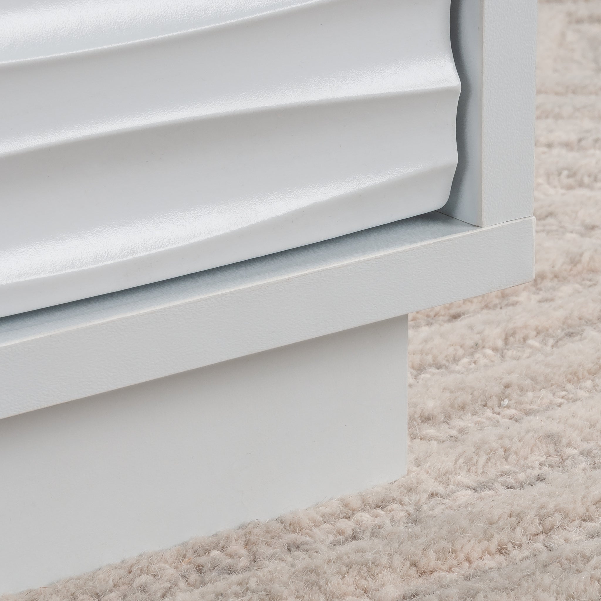 Close-up of the textured drawer front on the white coffee table, showcasing the coastal wave design and smooth white finish.