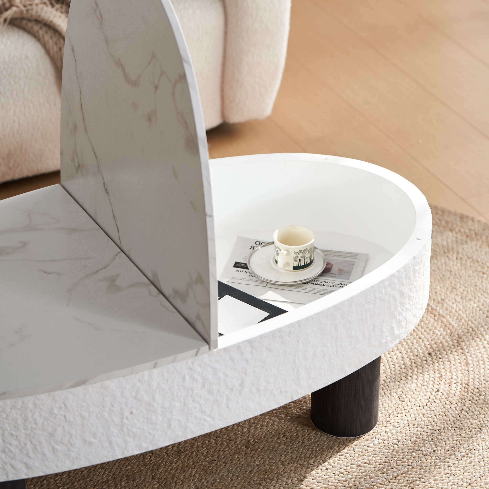 Close-up of the lift-top storage compartment in the oval coffee table with faux marble finish and modern design.