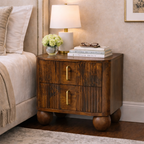 Dark brown solid wood nightstand with two fluted drawers, brass pulls, and rounded ball feet in a modern bedroom.