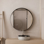 Single Round Black Metal Medicine Cabinet with Mirror above a stone sink in a minimalist beige bathroom.
