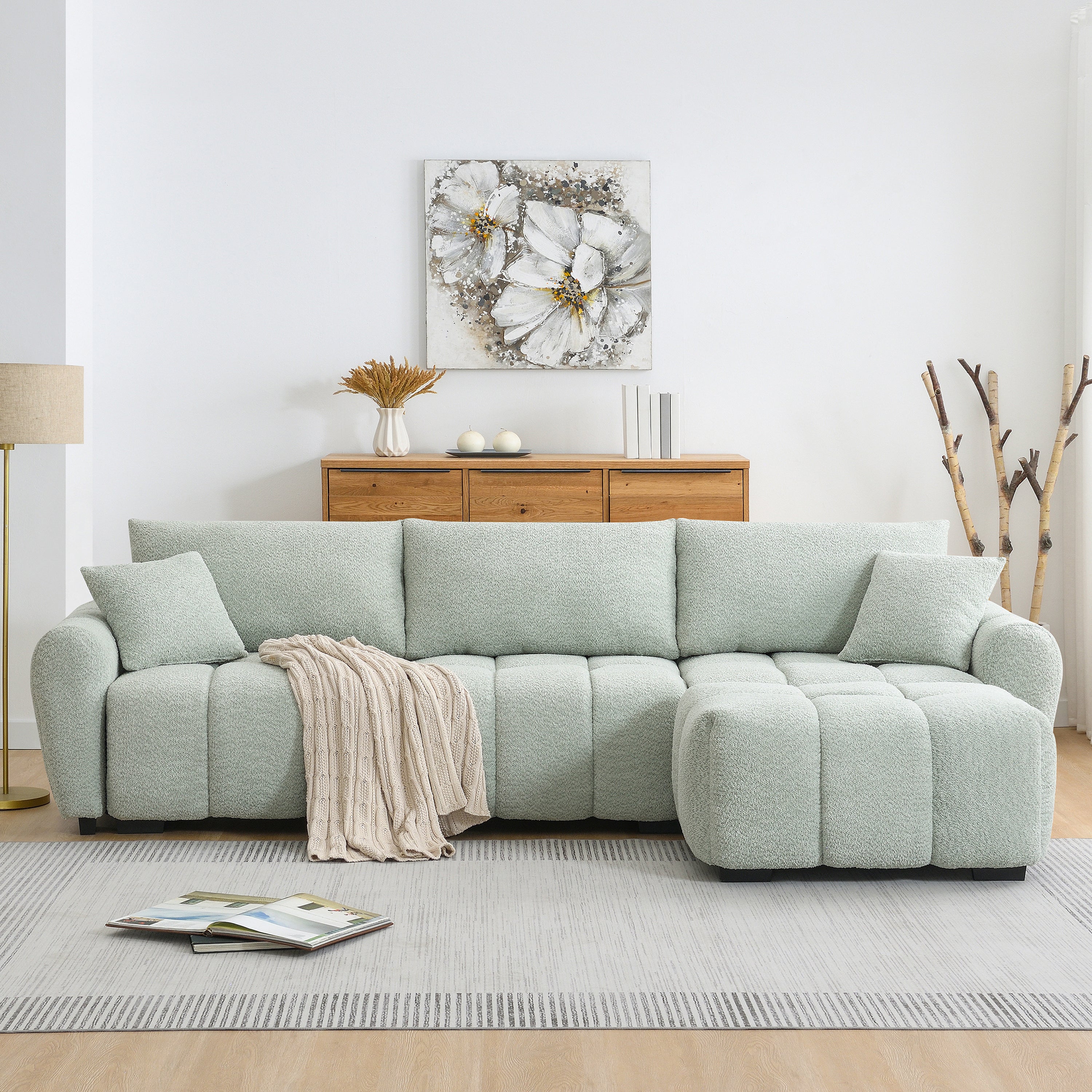 Full front view of modular sectional sofa with ottoman, featuring plush cushions and a cozy throw blanket on a neutral rug.