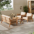 Four-piece acacia wood patio set with rope detailing, cream cushions, and a coffee table on a geometric outdoor rug.