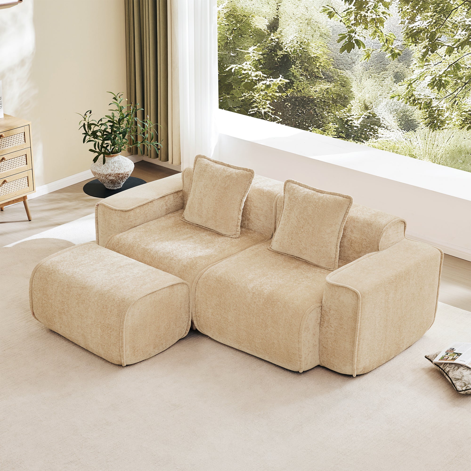 Velvet L Shape Modular Sofa with Ottoman and throw pillows in beige, placed in a sunlit living room with large windows and greenery view.