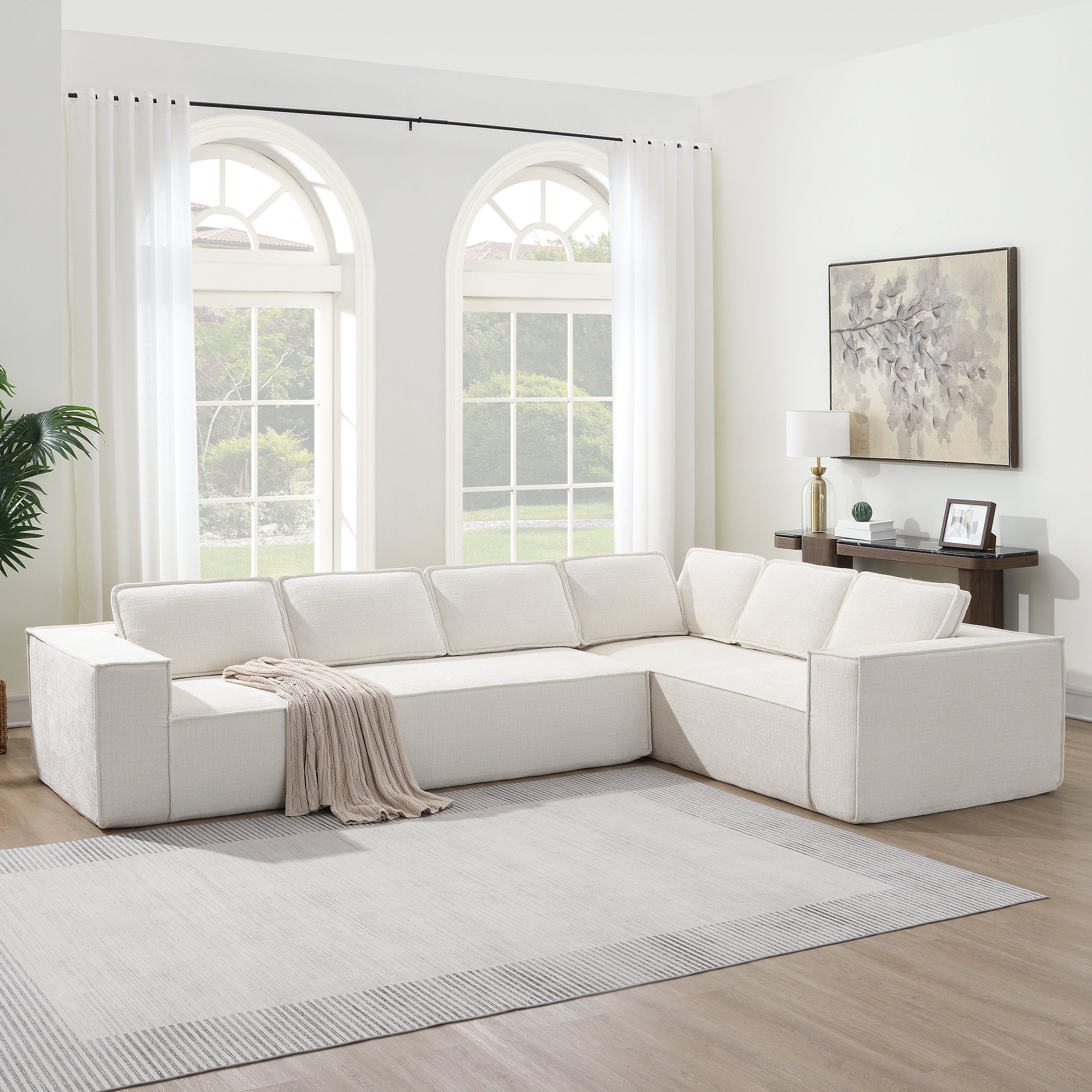 Minimalist modular sectional sofa in cream chenille fabric placed in a bright living room with large windows and neutral decor.