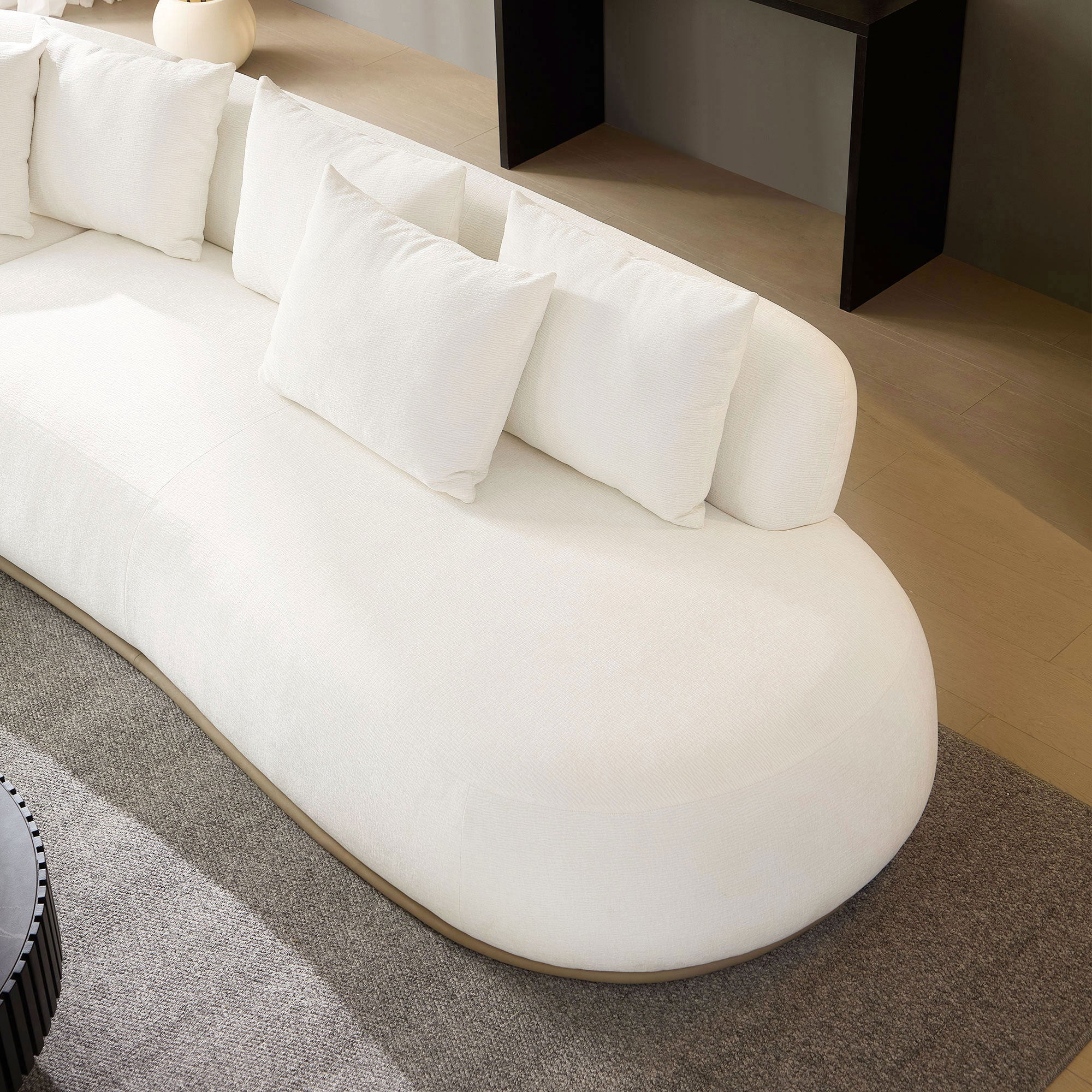 Back view of the beige L-shape sectional sofa showing its rounded design and multiple plush back cushions for full support.