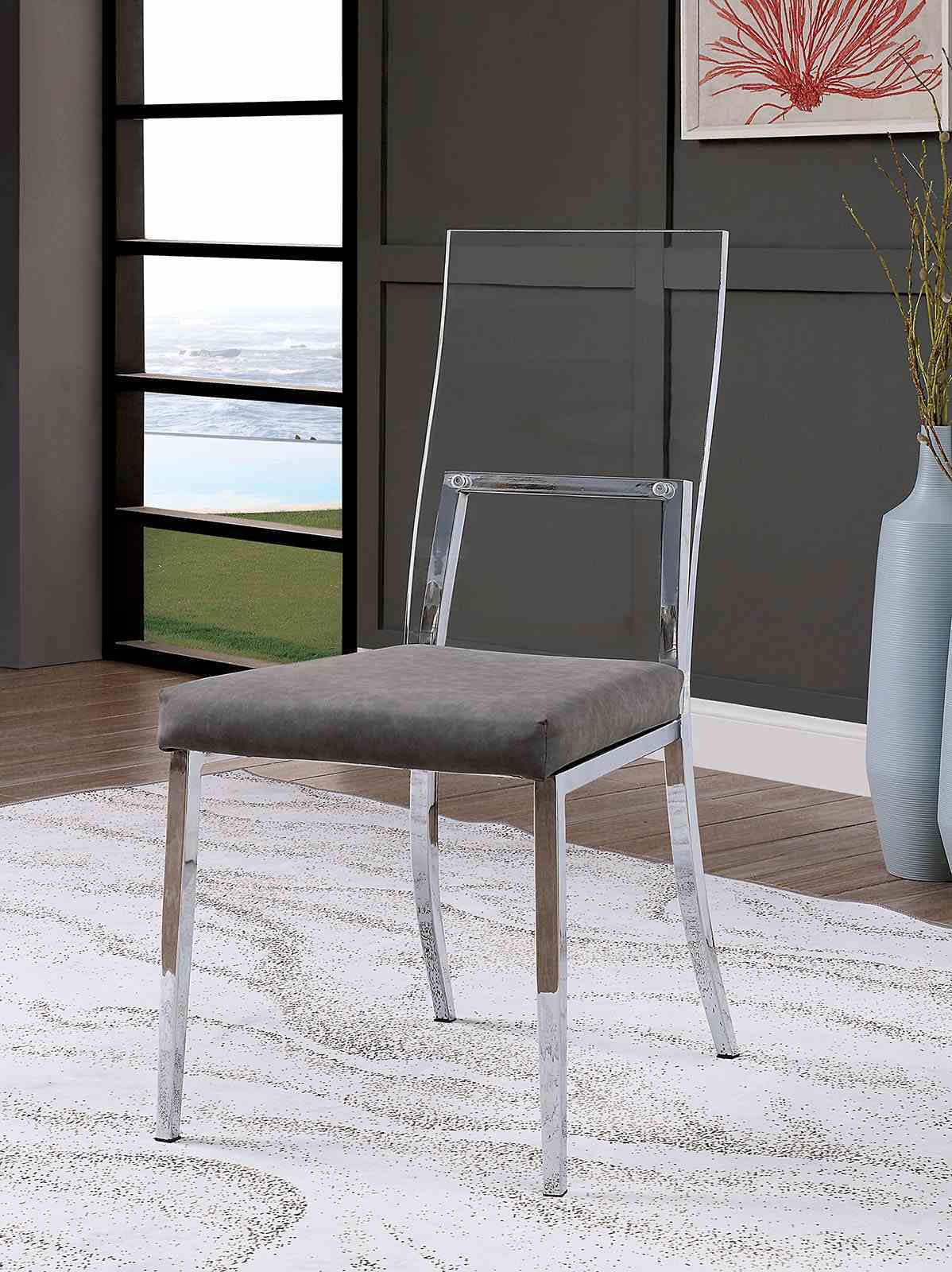 Minimalist chrome dining chair with acrylic backrest and gray cushion placed in a stylish, modern dining room.