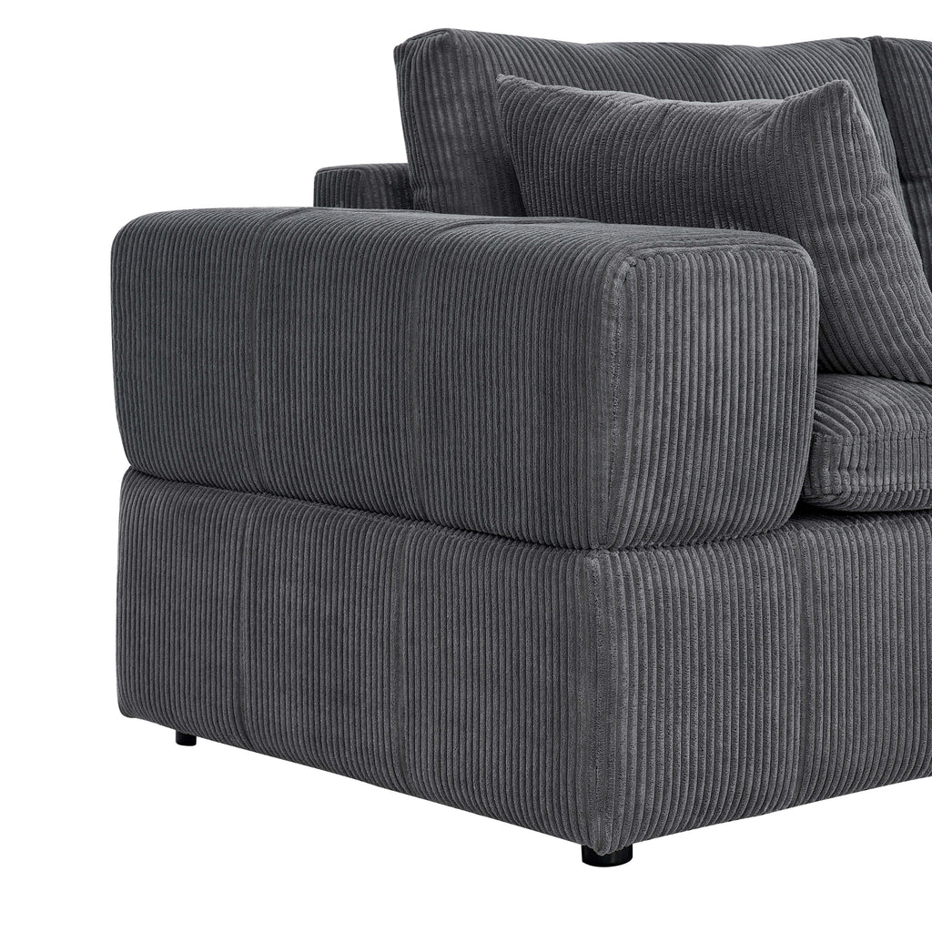 Detail of the wide armrest and cushion on the corduroy sectional. Emphasizes soft padding and ribbed fabric texture.