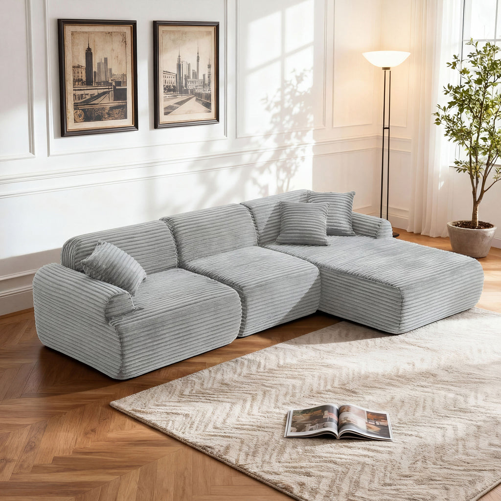 Modern gray corduroy L-shaped modular sectional sofa with plush, low-profile design on a patterned area rug.