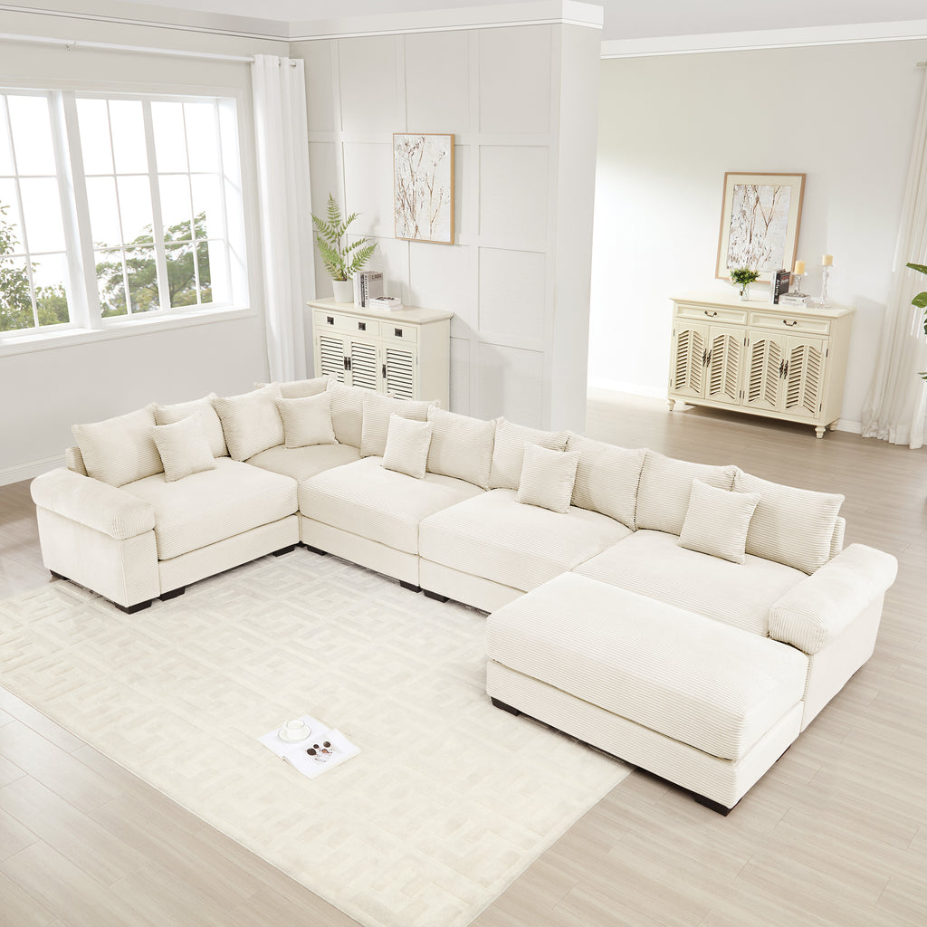Oversized cream corduroy modular sectional sofa with extra-wide armrests and plush cushions in a bright living room.