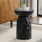 Black round accent table made of solid mango wood, featuring a textured, carved pedestal base and a smooth top.