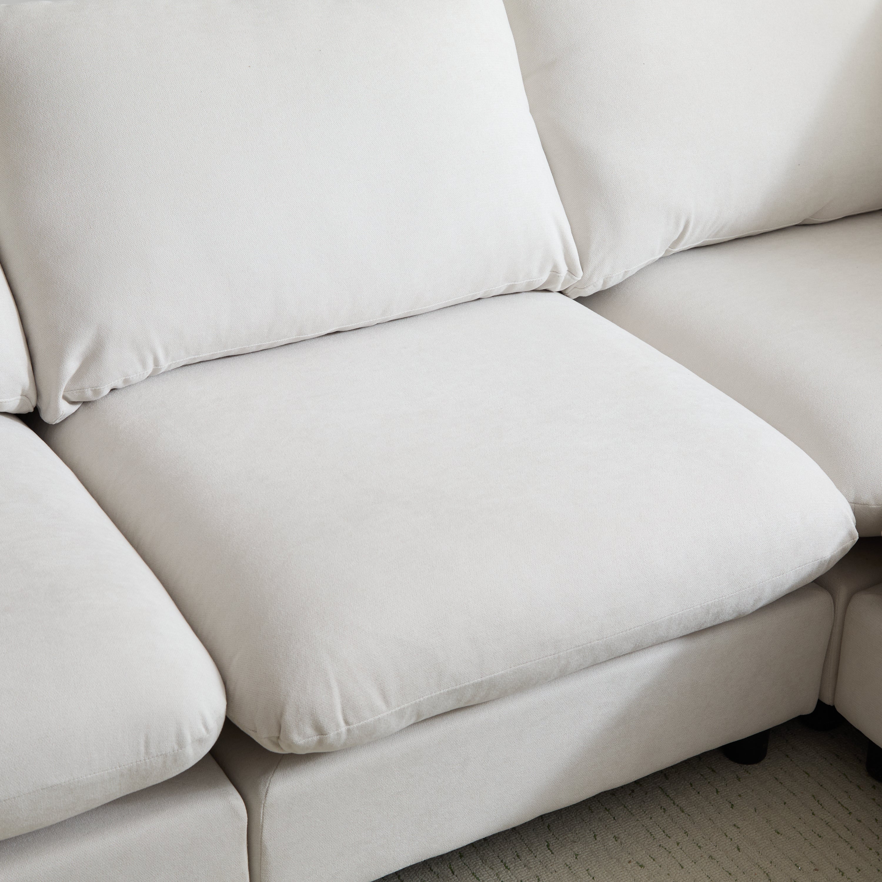 Detail of center seat cushion on the 99 in. modular sectional sofa, highlighting plush padding and smooth white fabric texture.
