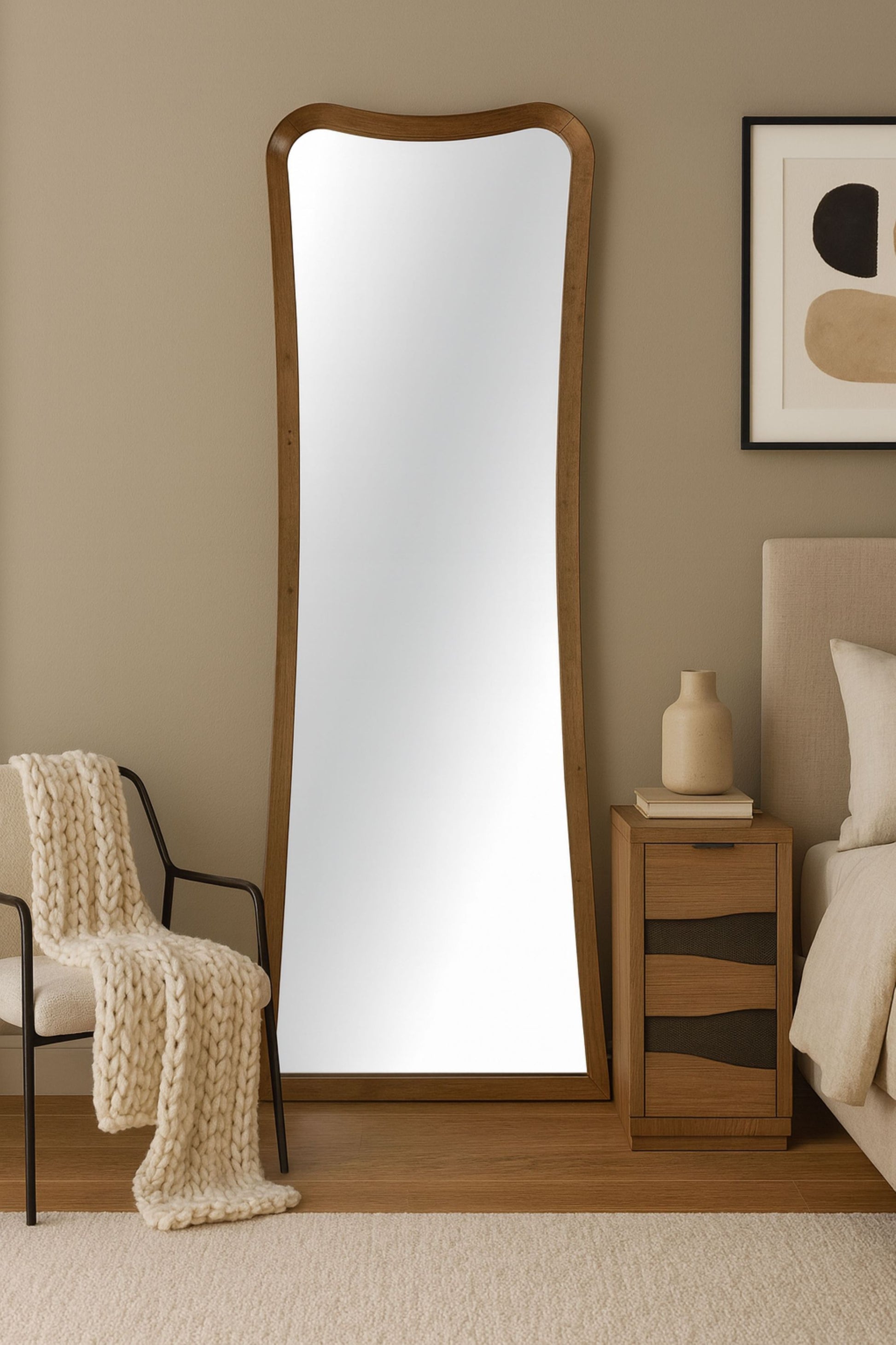 Elegant full-length floor mirror with wood frame leaning against a bedroom wall, enhancing cozy and modern interior decor.