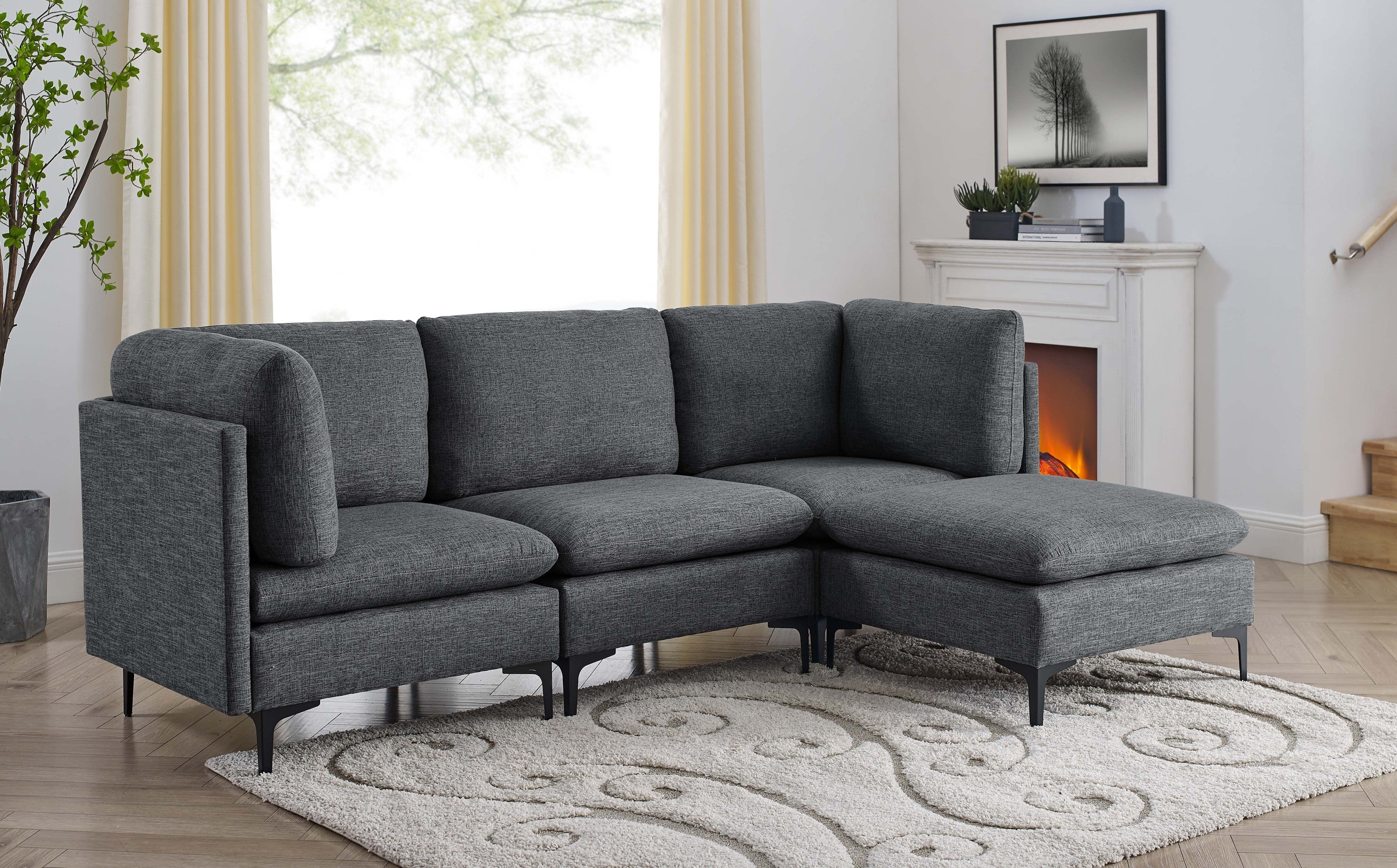 Modern charcoal grey linen modular sectional sofa with plush cushions and sleek black metal legs in a living room.