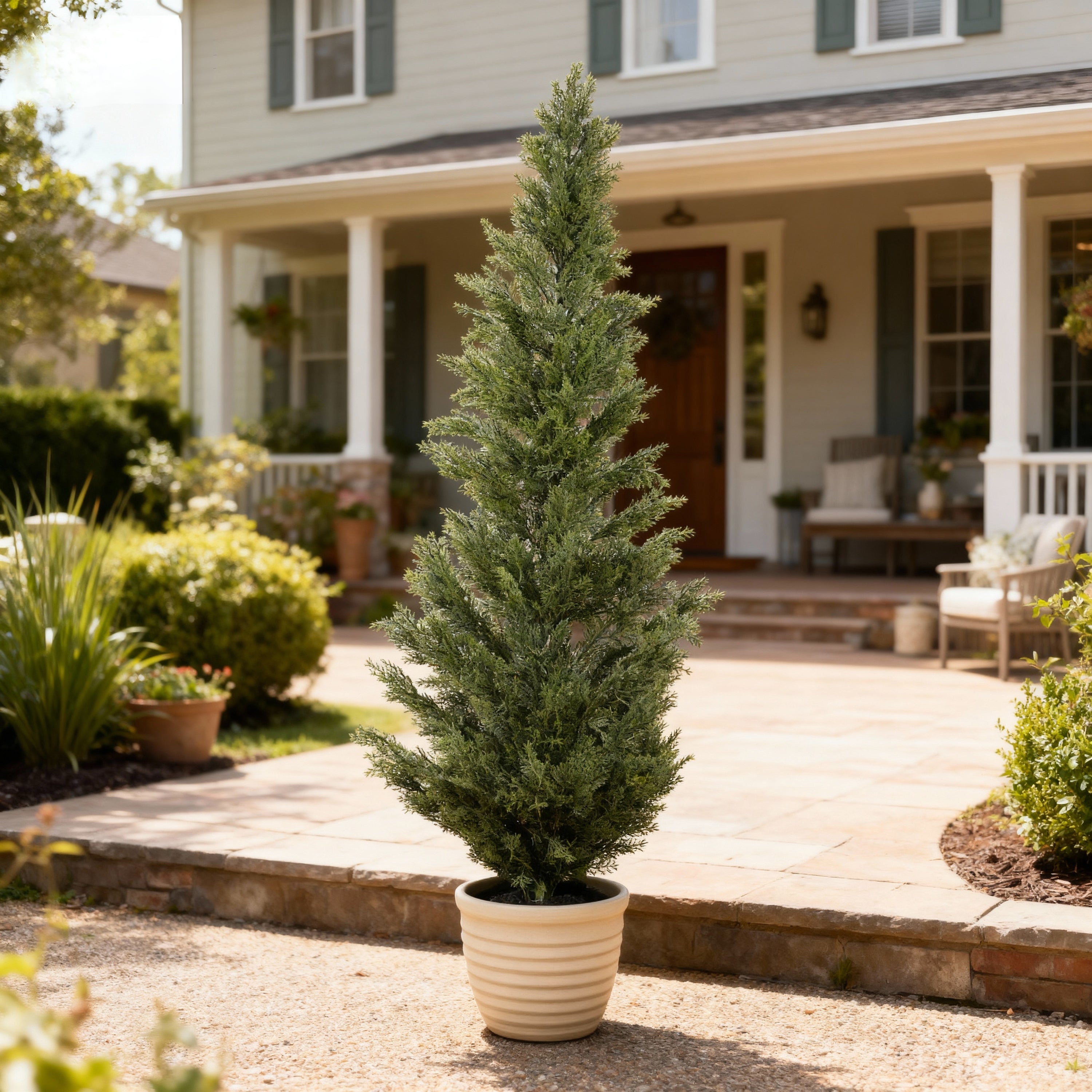 A 60-inch tall realistic artificial cypress topiary tree in a ribbed beige pot, set on a patio in front of a house.