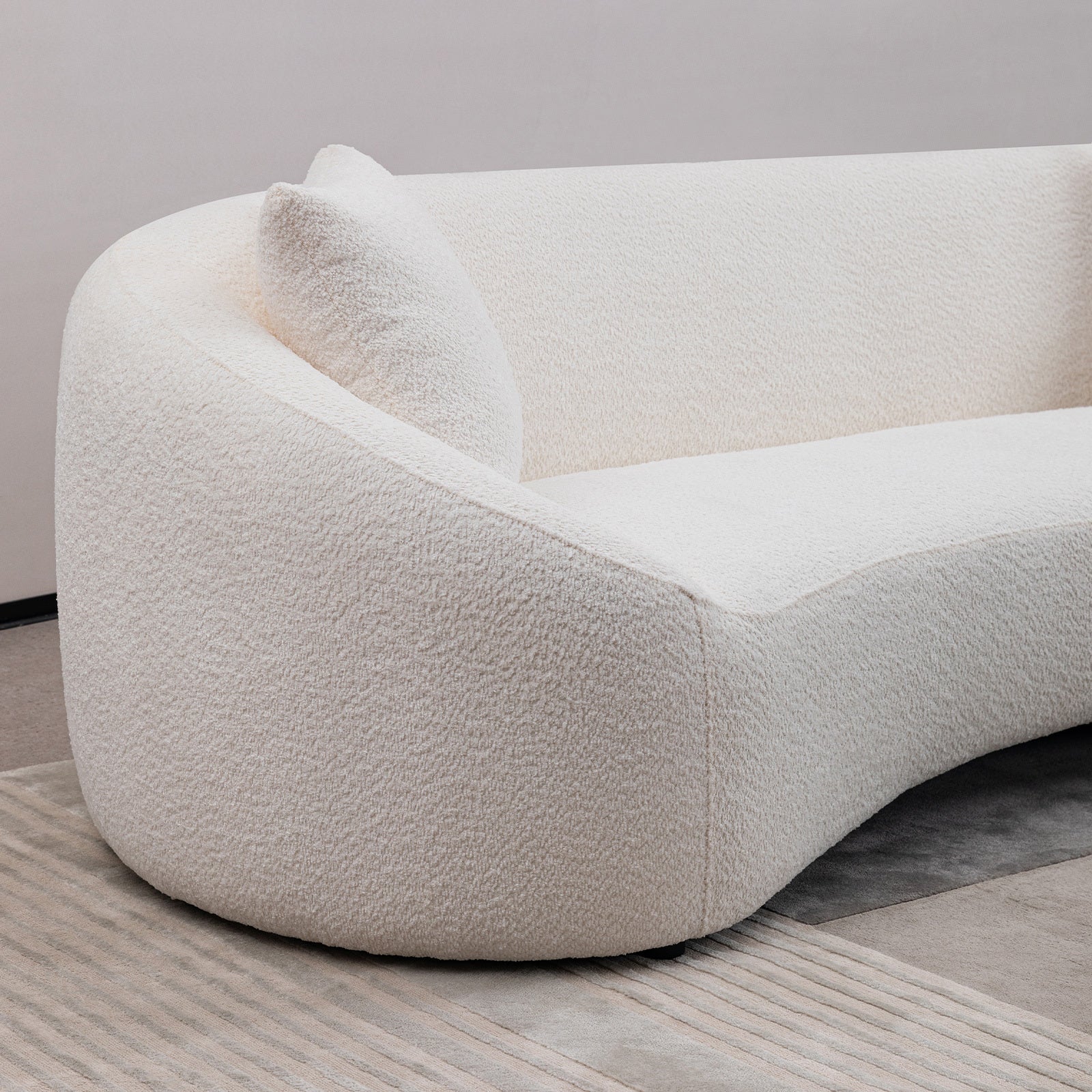 Close-up of the backrest and armrest curve on modern white sofa, showcasing its elegant minimalist design.