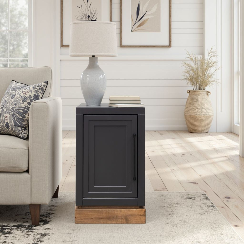 Nora Chairside Table - Black Whiskey Finish next to a beige couch in a bright room, showcasing its compact and stylish design.