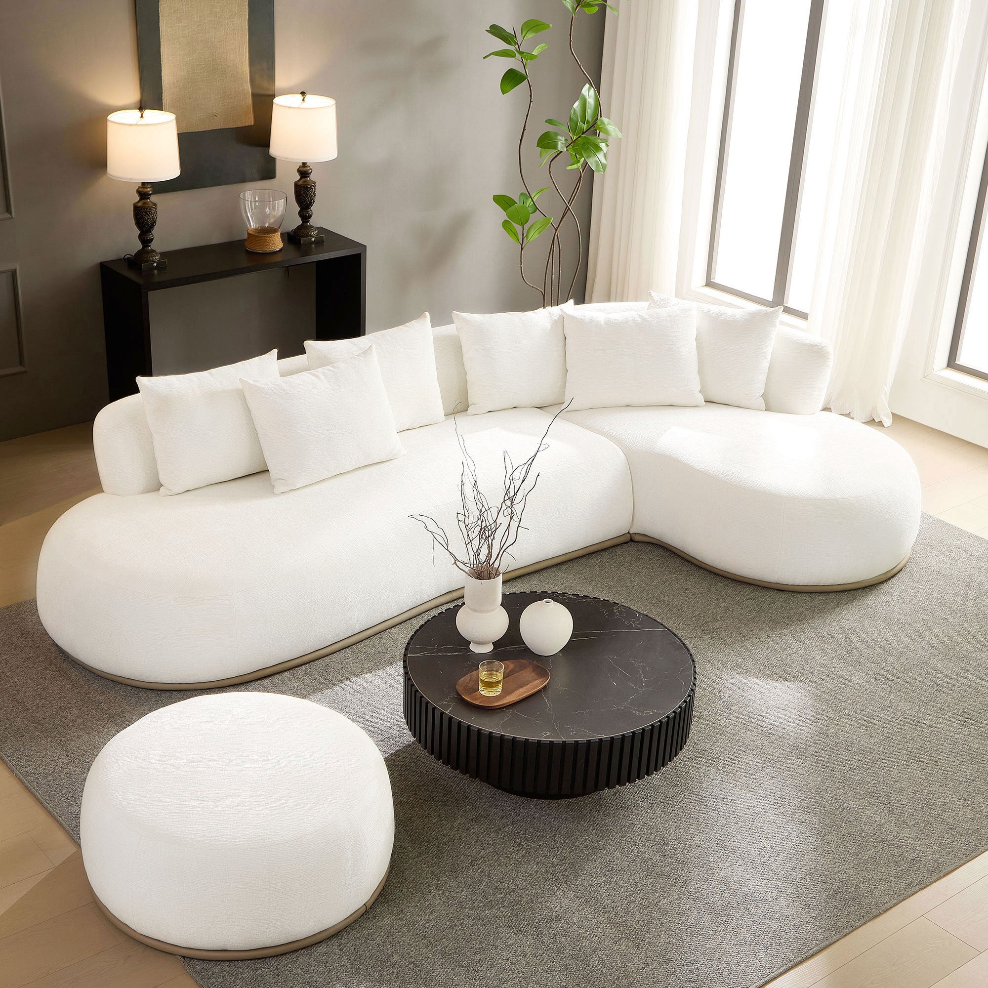 Contemporary oversized L-shape sectional sofa in beige with ottoman, styled in a cozy living space with neutral tones and soft lighting.