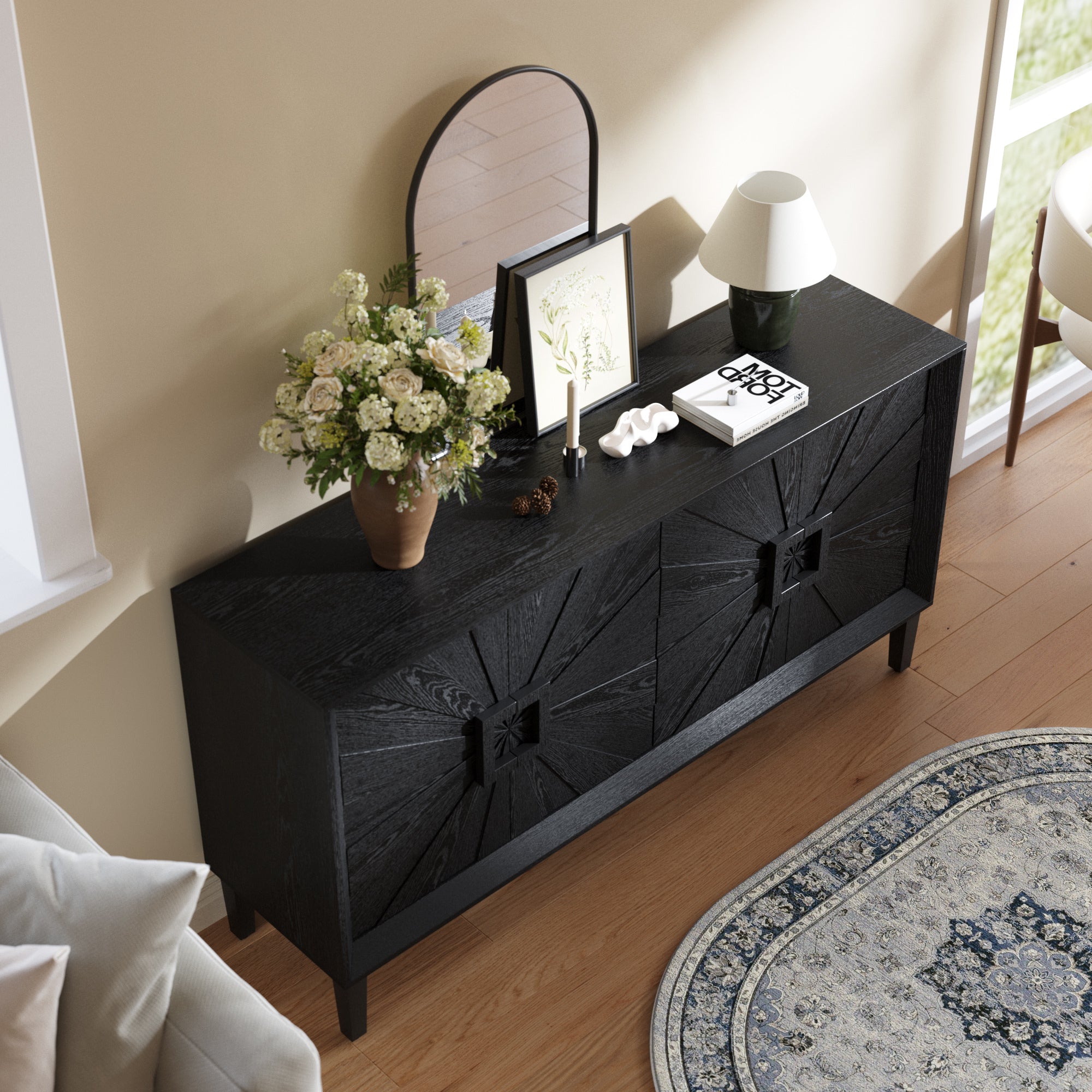 Top view of Black Farmhouse Credenza with Sunburst Door Design, decorated with books, flowers, and a lamp for stylish home storage.