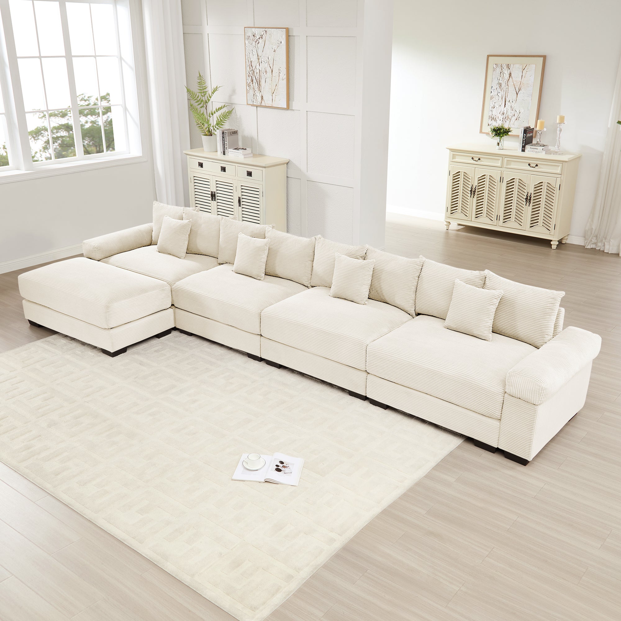 Oversized L-shape cream corduroy sectional with deep seats, wide armrests, and multiple matching throw pillows.