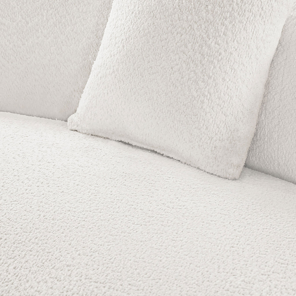 Close-up of white bouclé fabric and cushion texture on modern curved sofa set, emphasizing soft, luxurious upholstery.
