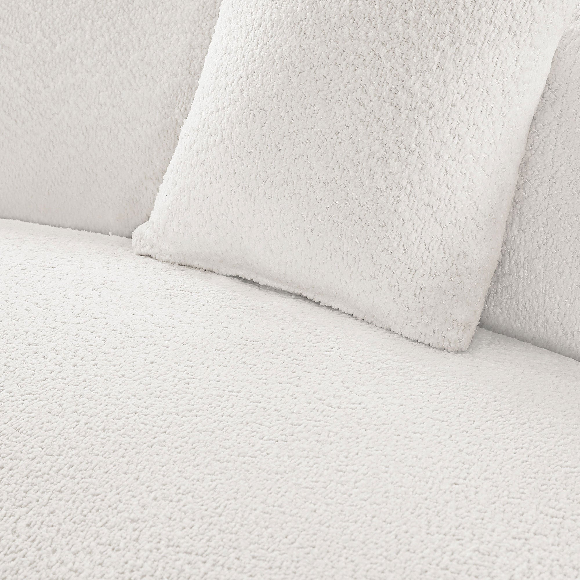 Close-up of white bouclé fabric and cushion texture on modern curved sofa set, emphasizing soft, luxurious upholstery.
