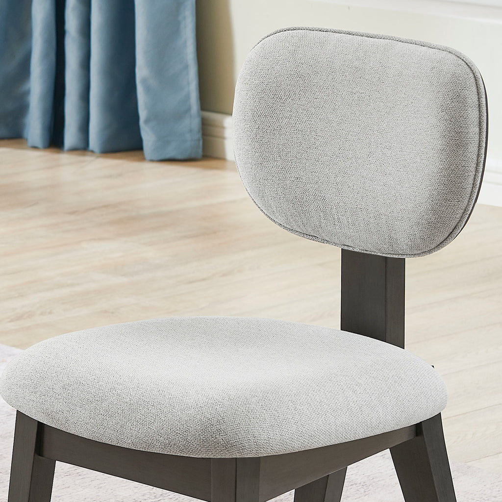Detail of the Valencia Dining Set chair's padded gray fabric backrest and seat, designed for comfort and modern aesthetics.